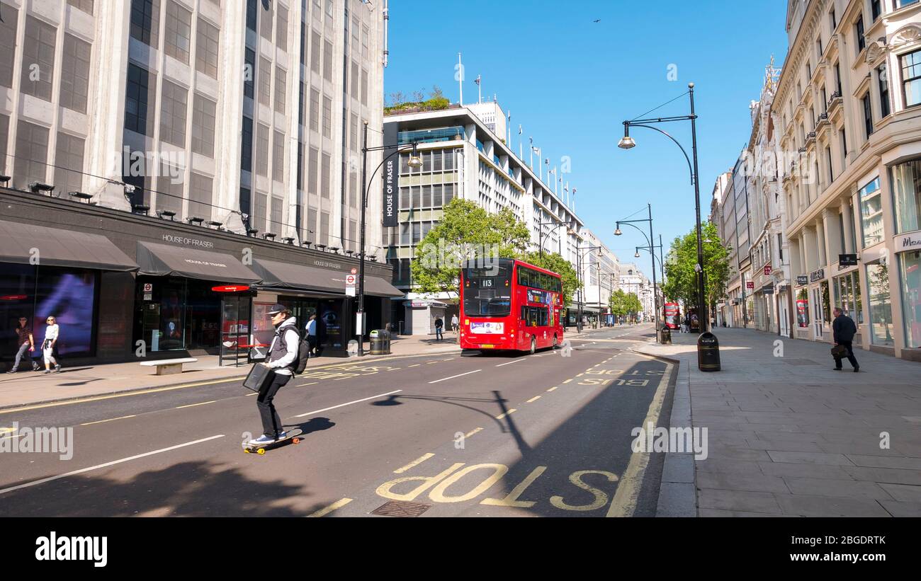 Skate boarder in Oxford Street, Coronavirus Pandemic in London  April 2020. No people , a few buses  in the streets, all shops closed during lockdown Stock Photo