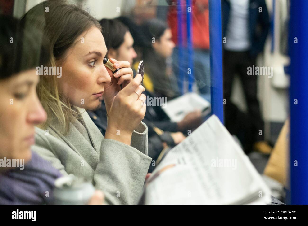 Profile view of a women applying makeup on the Northern Line of the London Underground Stock Photo