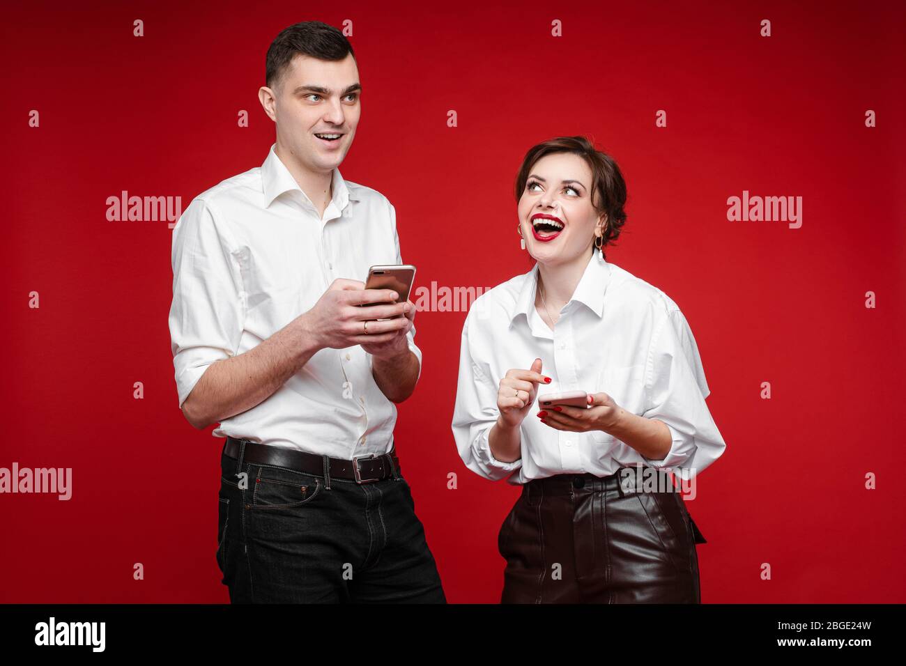 Happy young couple with gadgets standing in studio Stock Photo