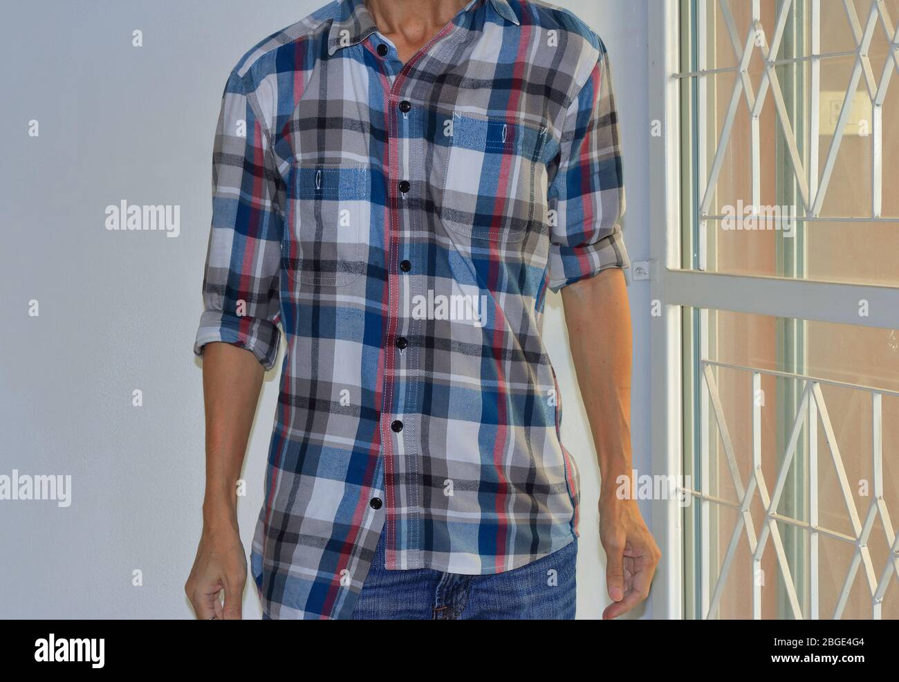 Man wearing buttoned wrong and rolled up sleeves plaid shirt, mistake or intend to break the rule Stock Photo