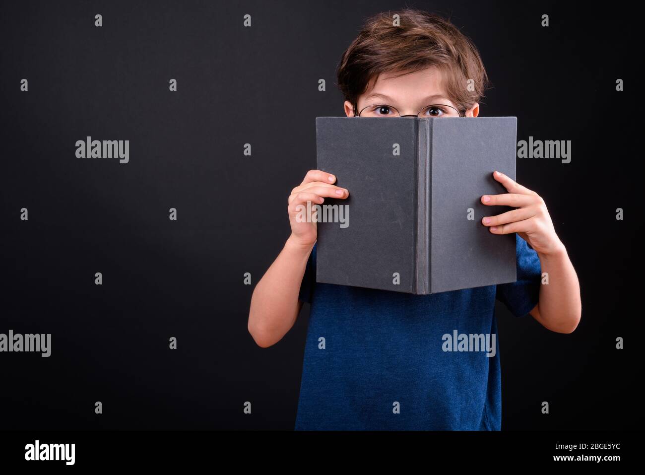 Portrait of shy young boy covering face with book Stock Photo