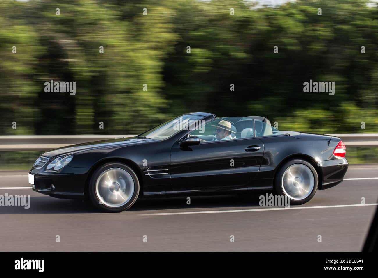 Black cabriolet driving across trees,blurred view Stock Photo