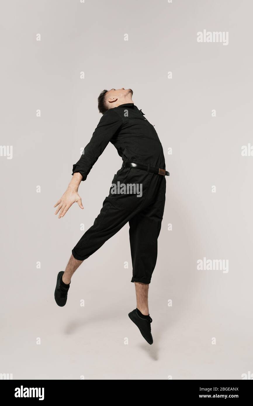 I did it. Full length of confident young man in black clothes jumping, walking against white background Stock Photo