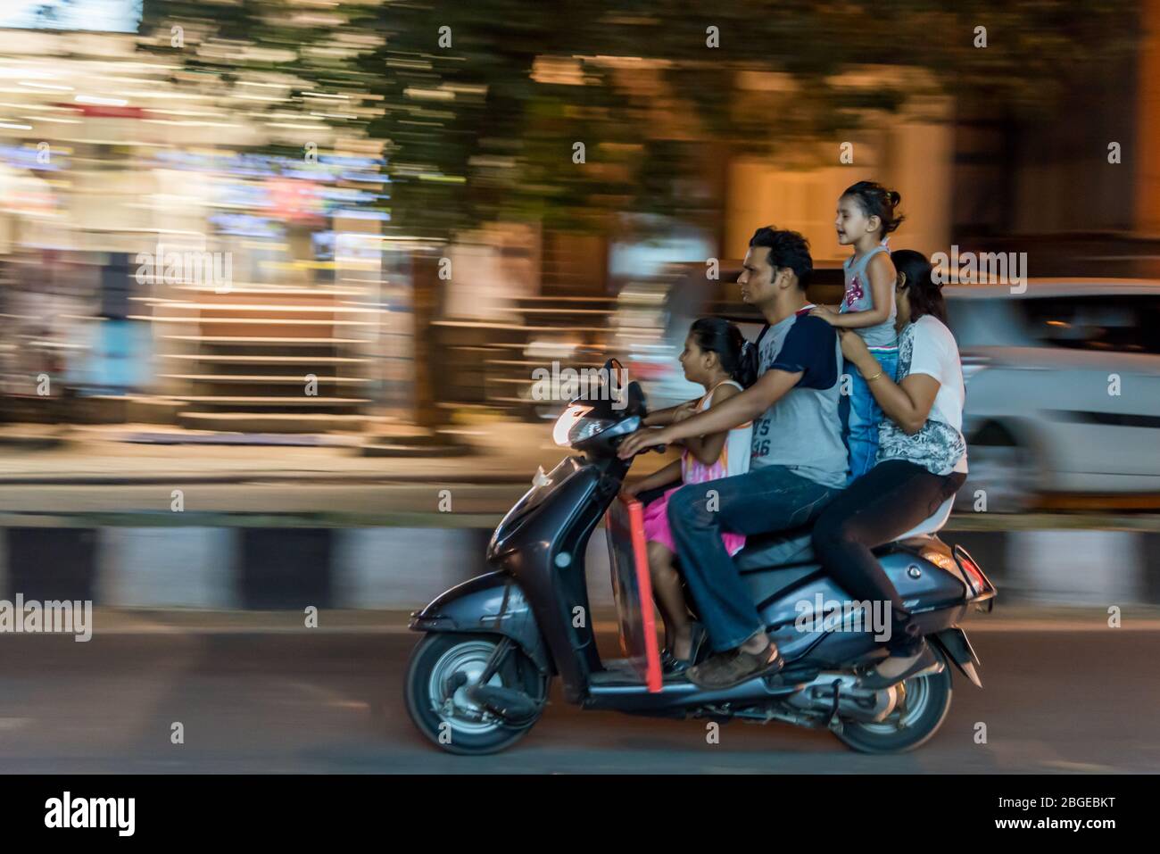 People Riding Without Helments Sign Grainy motion blur shot of a family of four riding on a scooter without ...