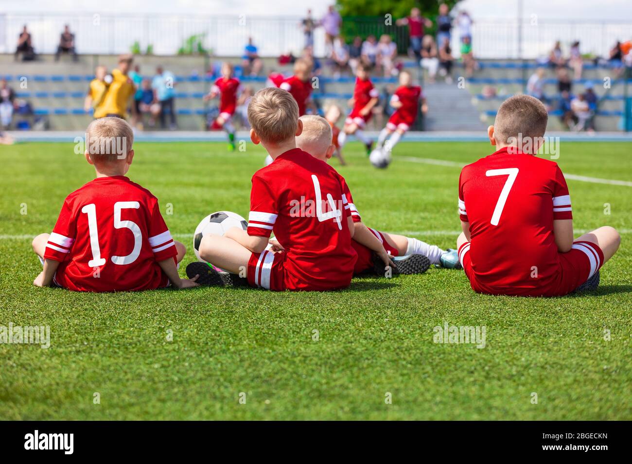 Junior Level Kids Sports Team Sitting on Grass Field. Football Soccer