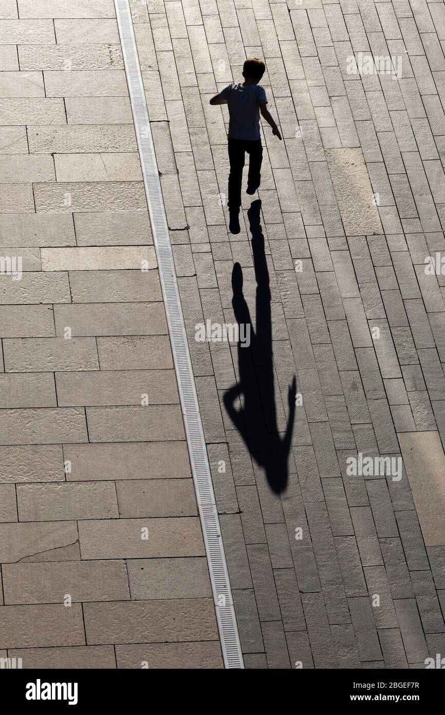 A child jumping and casting a long shadow outside the Southbank Centre, South Bank, London Stock Photo