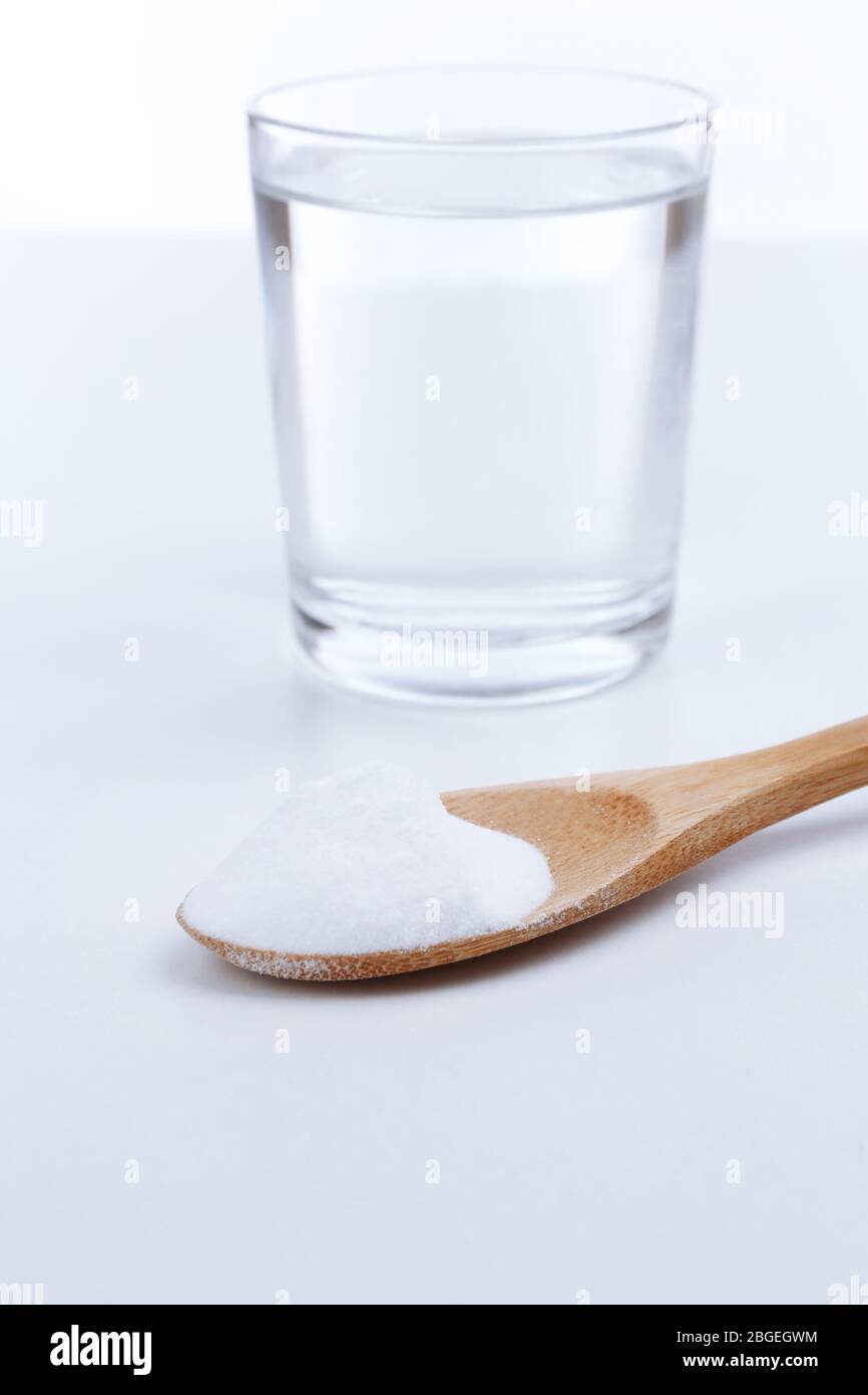 Spoon of baking soda over glass of water, isolated on white Stock Photo