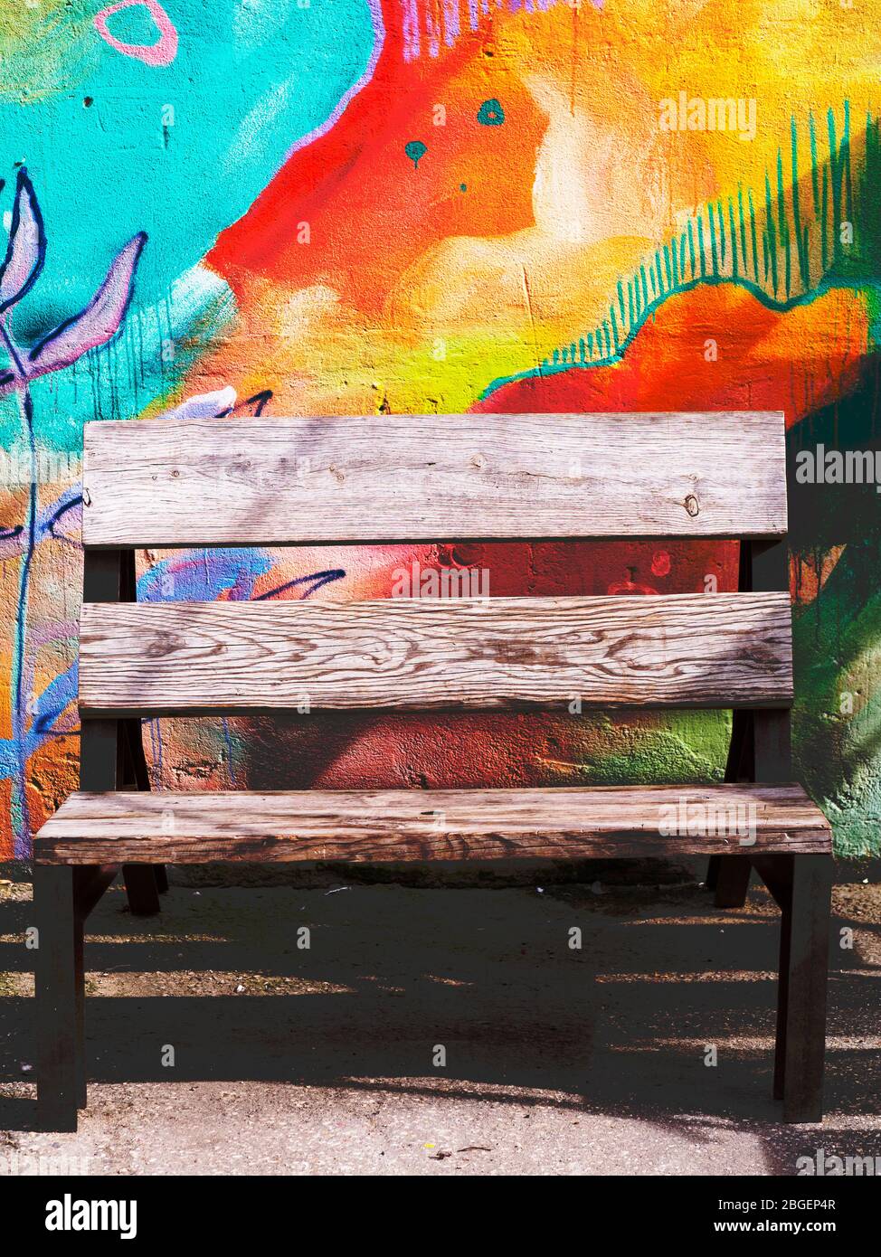 Narrow wooden bench against colorful artistic background wall Stock Photo