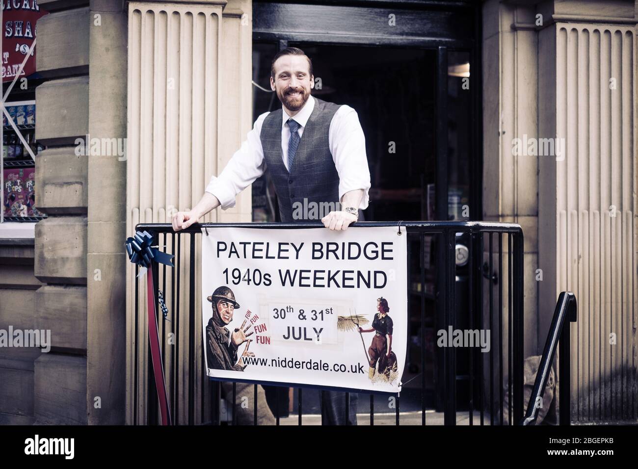 A man, in a waistcoat, stands by the sign for Pateley Bridge 1940s Weekend Stock Photo
