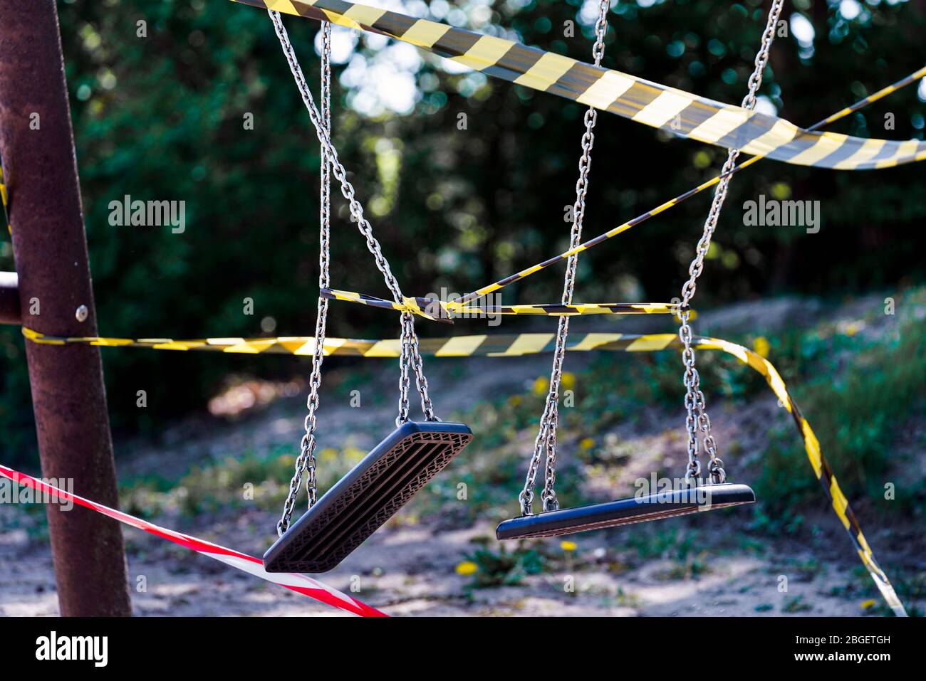 Dortmund, 21.4.2020: Mit Flatterband festgebundene Kinderschaukeln auf einem wegen der Coronavirus Krise (Covid-19, SARS-CoV-2) und zum Schutz vor Neuinfektionen gesperrten Kinderspielplatz in einer Kleingartenanlage in Dortmund. --- Dortmund, Germany, April 21, 2020: Children's swings tied with ribbons at a children's playground in Dortmund. Closed due to the coronavirus crisis (Covid-19, SARS-CoV-2) and to protect against new infections. Stock Photo