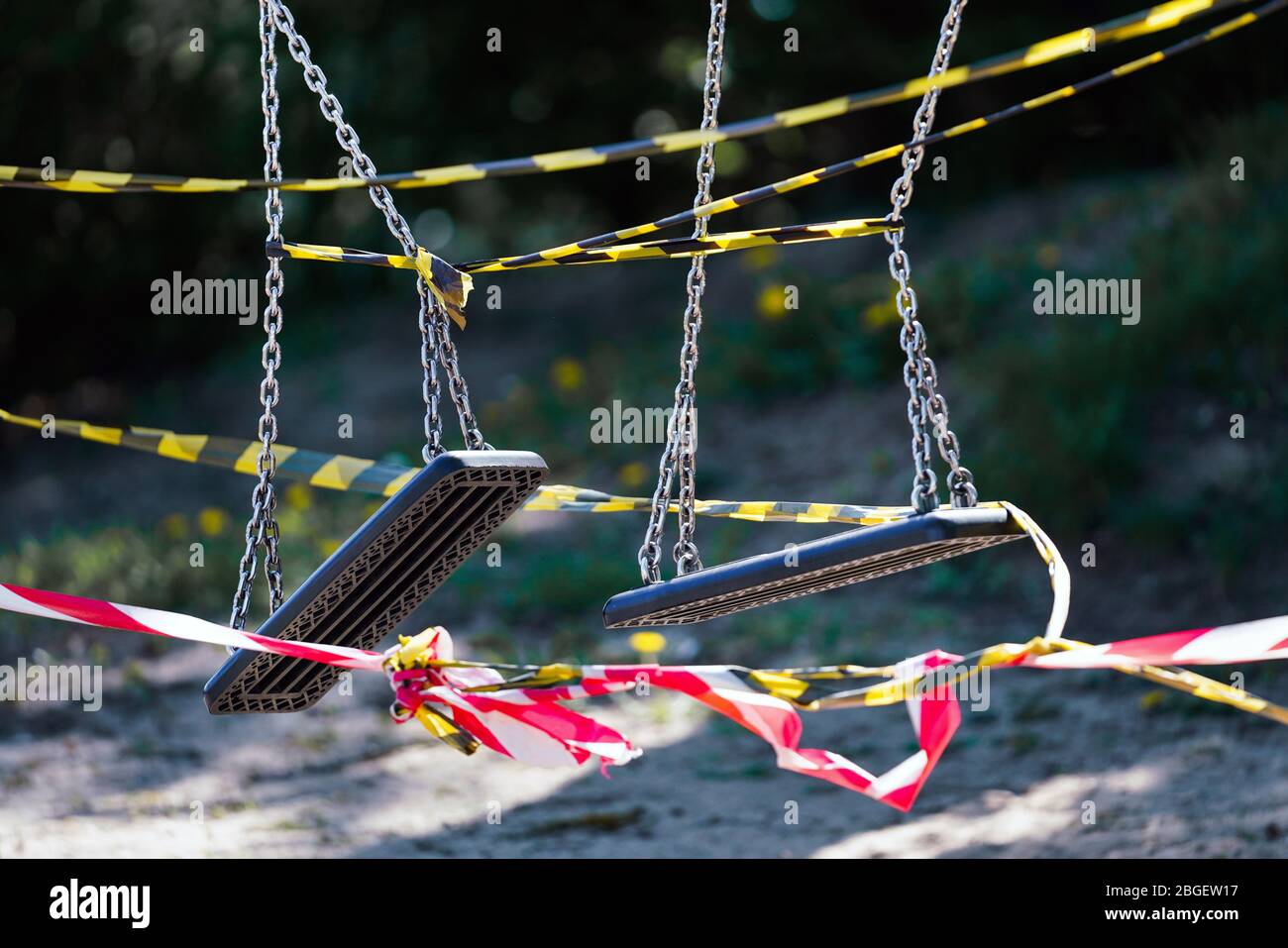 Dortmund, 21.4.2020: Mit Flatterband festgebundene Kinderschaukeln auf einem wegen der Coronavirus Krise (Covid-19, SARS-CoV-2) und zum Schutz vor Neuinfektionen gesperrten Kinderspielplatz in einer Kleingartenanlage in Dortmund. --- Dortmund, Germany, April 21, 2020: Children's swings tied with ribbons at a children's playground in Dortmund. Closed due to the coronavirus crisis (Covid-19, SARS-CoV-2) and to protect against new infections. Stock Photo