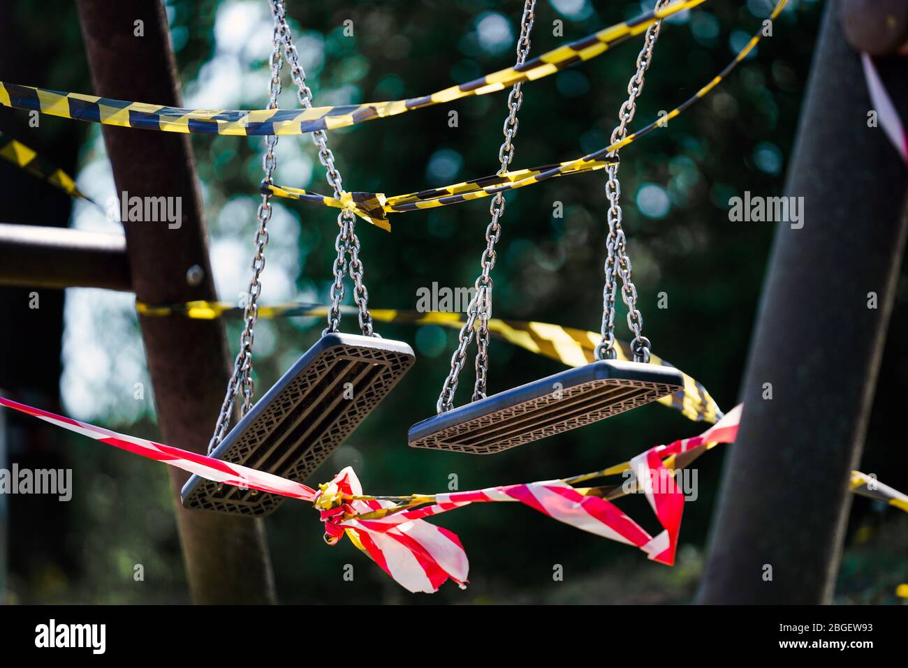 Dortmund, 21.4.2020: Mit Flatterband festgebundene Kinderschaukeln auf einem wegen der Coronavirus Krise (Covid-19,  SARS-CoV-2) und zum Schutz vor Neuinfektionen gesperrten Kinderspielplatz in einer Kleingartenanlage in Dortmund.   ---   Dortmund, Germany, April 21, 2020: Children's swings tied with ribbons at a children's playground in Dortmund. Closed due to the coronavirus crisis (Covid-19, SARS-CoV-2) and to protect against new infections. Stock Photo