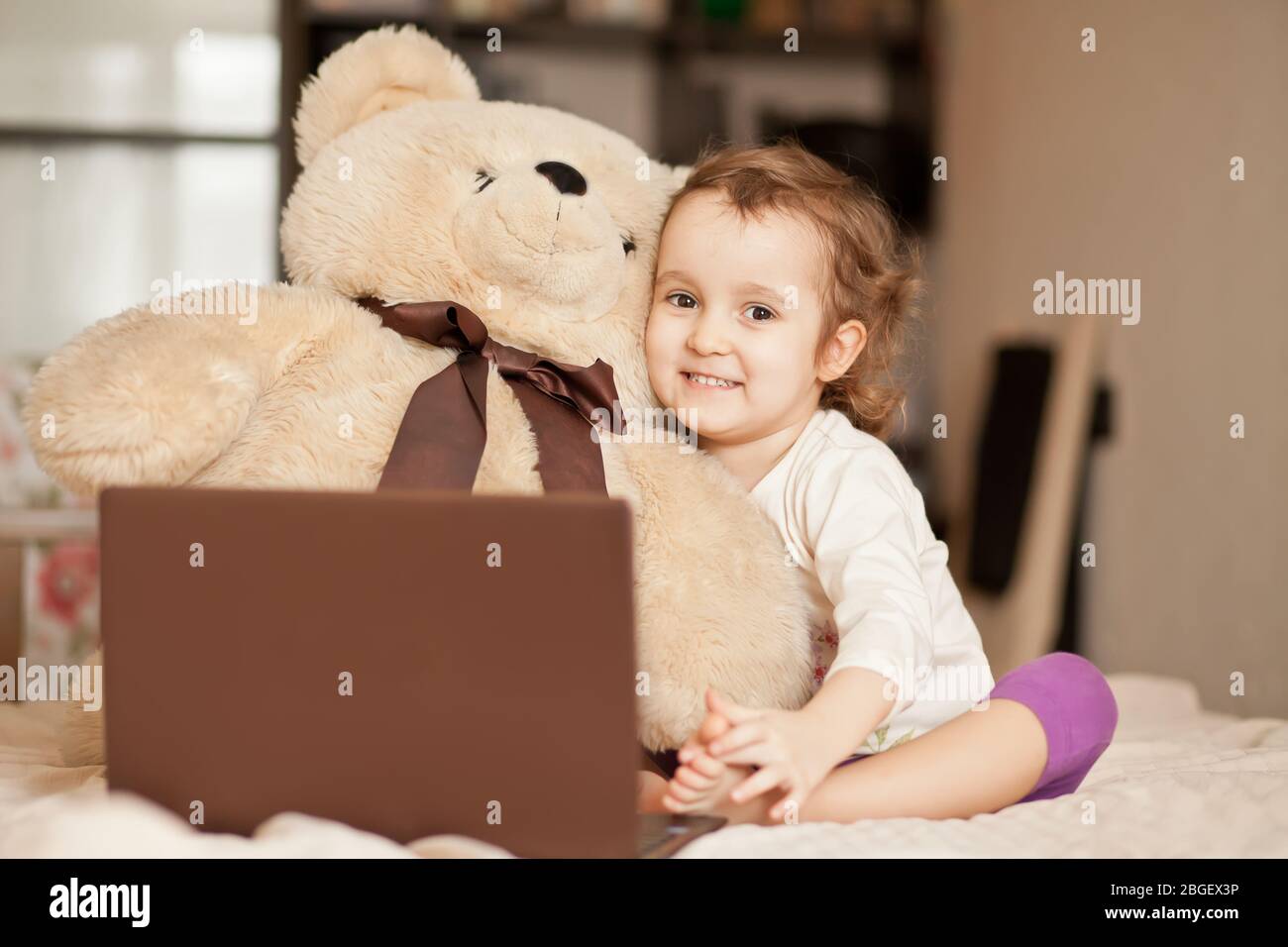 Little Cute Girl Sitting On The Bed With Big Teddy Bear Toy And Using A Digital Tablet Laptop Notebook Online Call Friends Or Parents Stock Photo Alamy