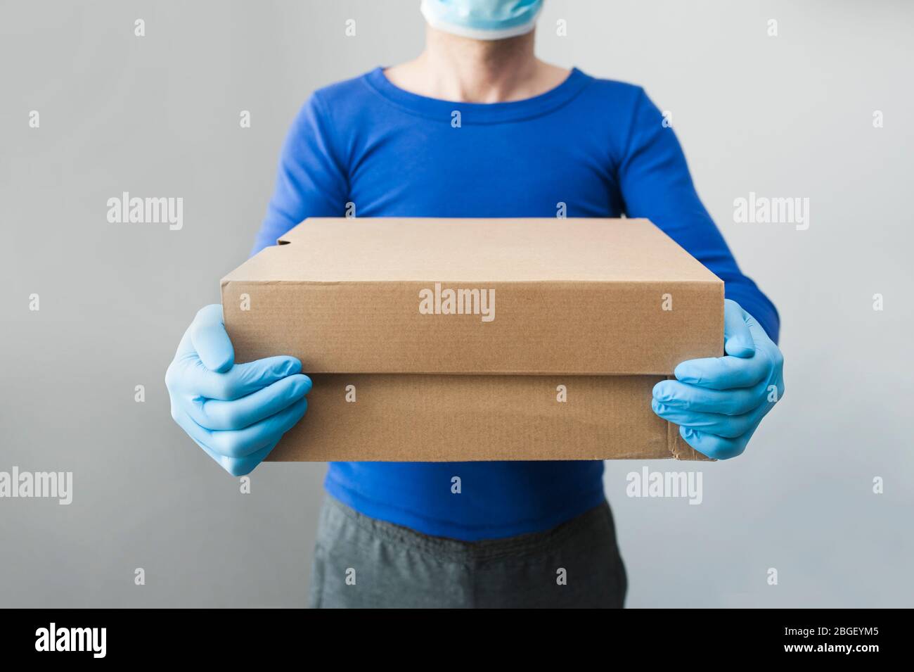 Delivery man holding cardboard boxes in medical rubber gloves and mask. copy space. Fast and free Delivery transport. Online shopping and Express Stock Photo