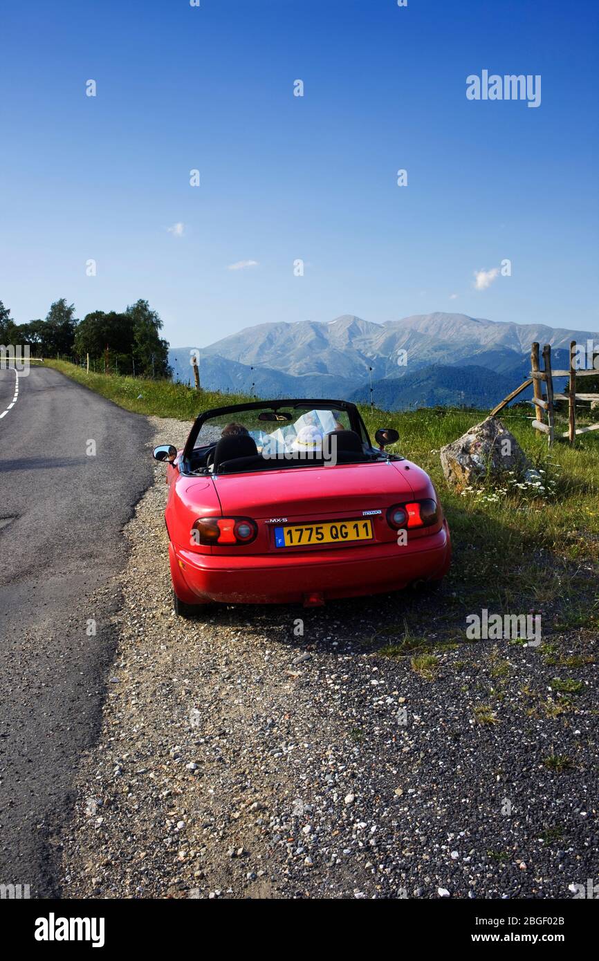 Red car in Coll d'Ares with Canigó peak at distance. Pyrenees, Catalonia, Catalogne (France, Europe) Stock Photo
