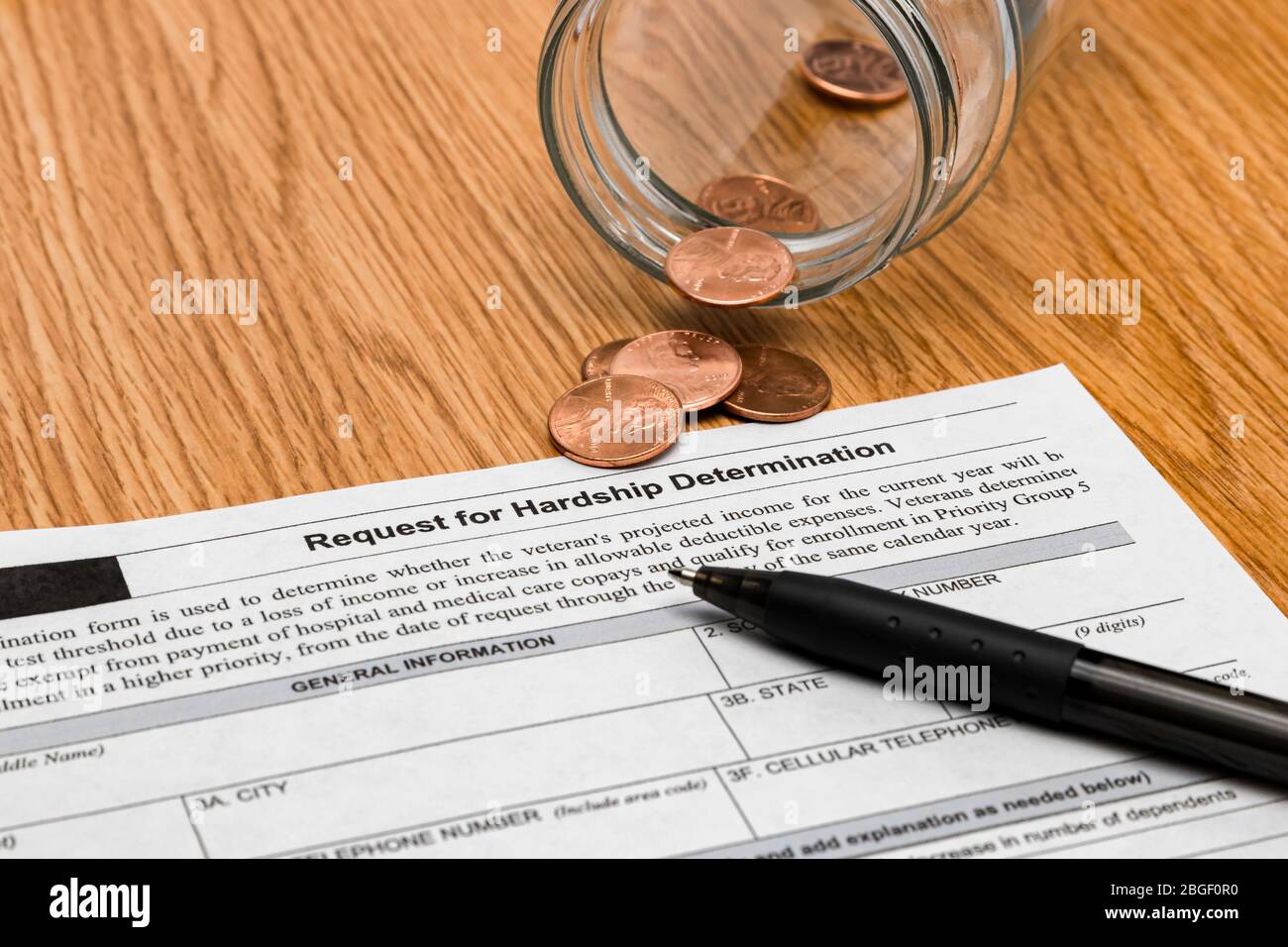 Financial hardship application, empty savings jar and coins. Concept of unemployment, recession and debt during Covid-19 coronavirus pandemic Stock Photo