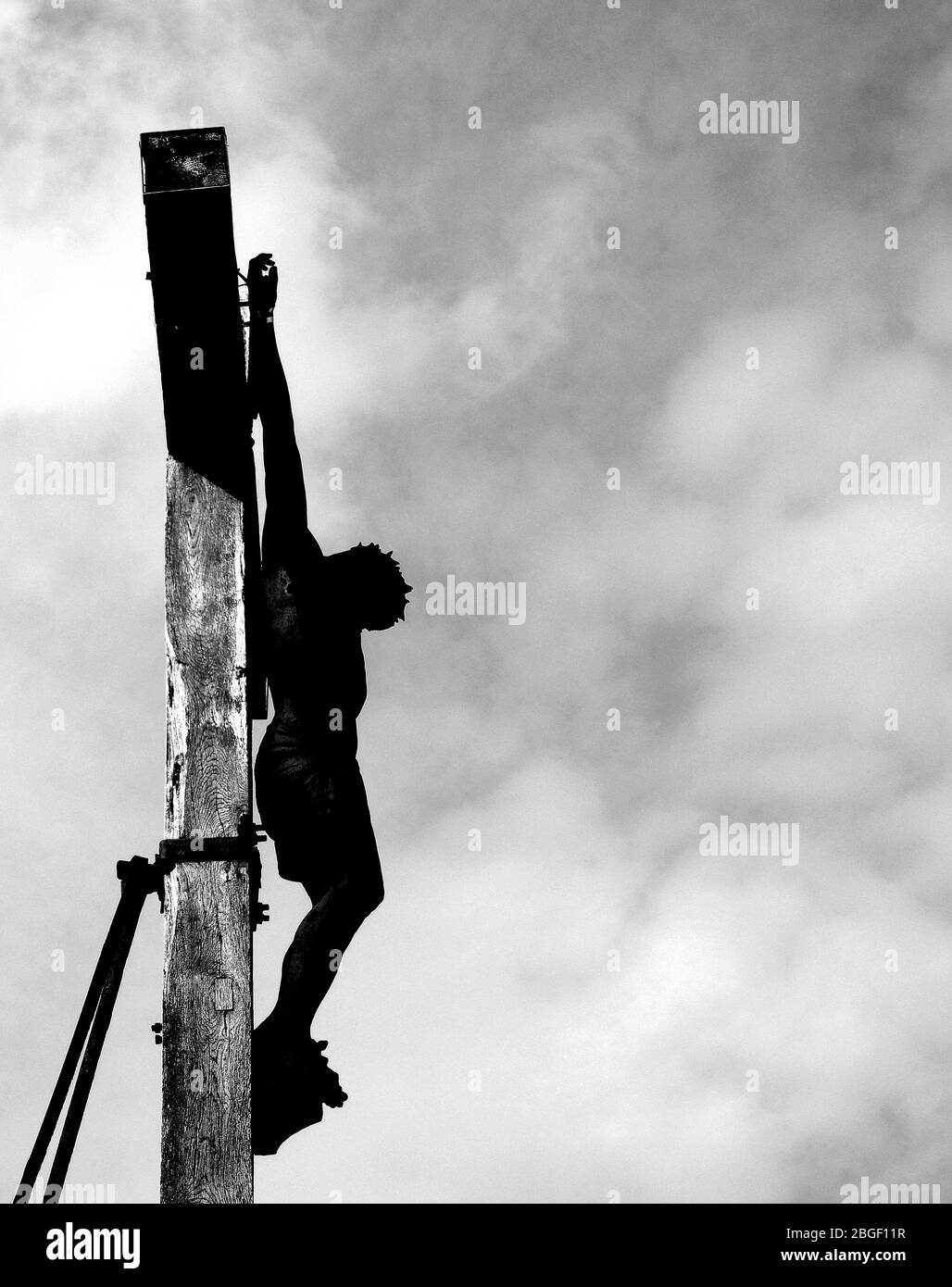 Crucifix with gilded sculpture of Jesus on wooden cross against dark  sky. Stock Photo