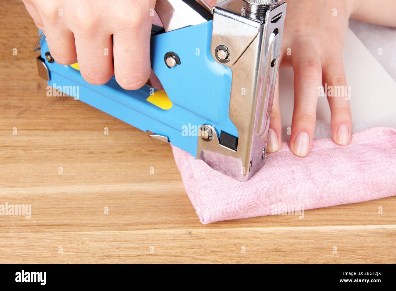Fastening fabric and board using construction stapler Stock Photo