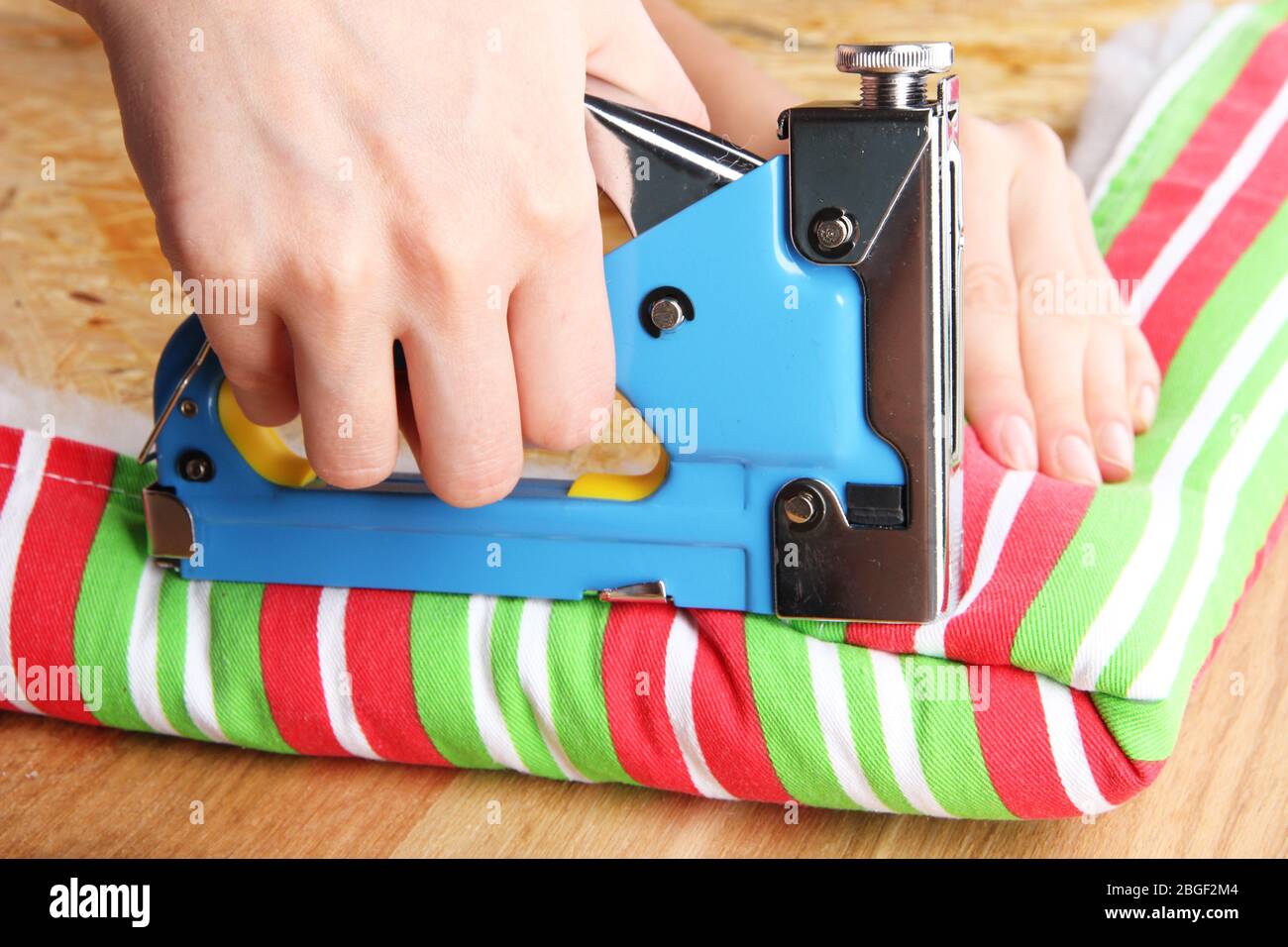 Fastening fabric and board using construction stapler Stock Photo