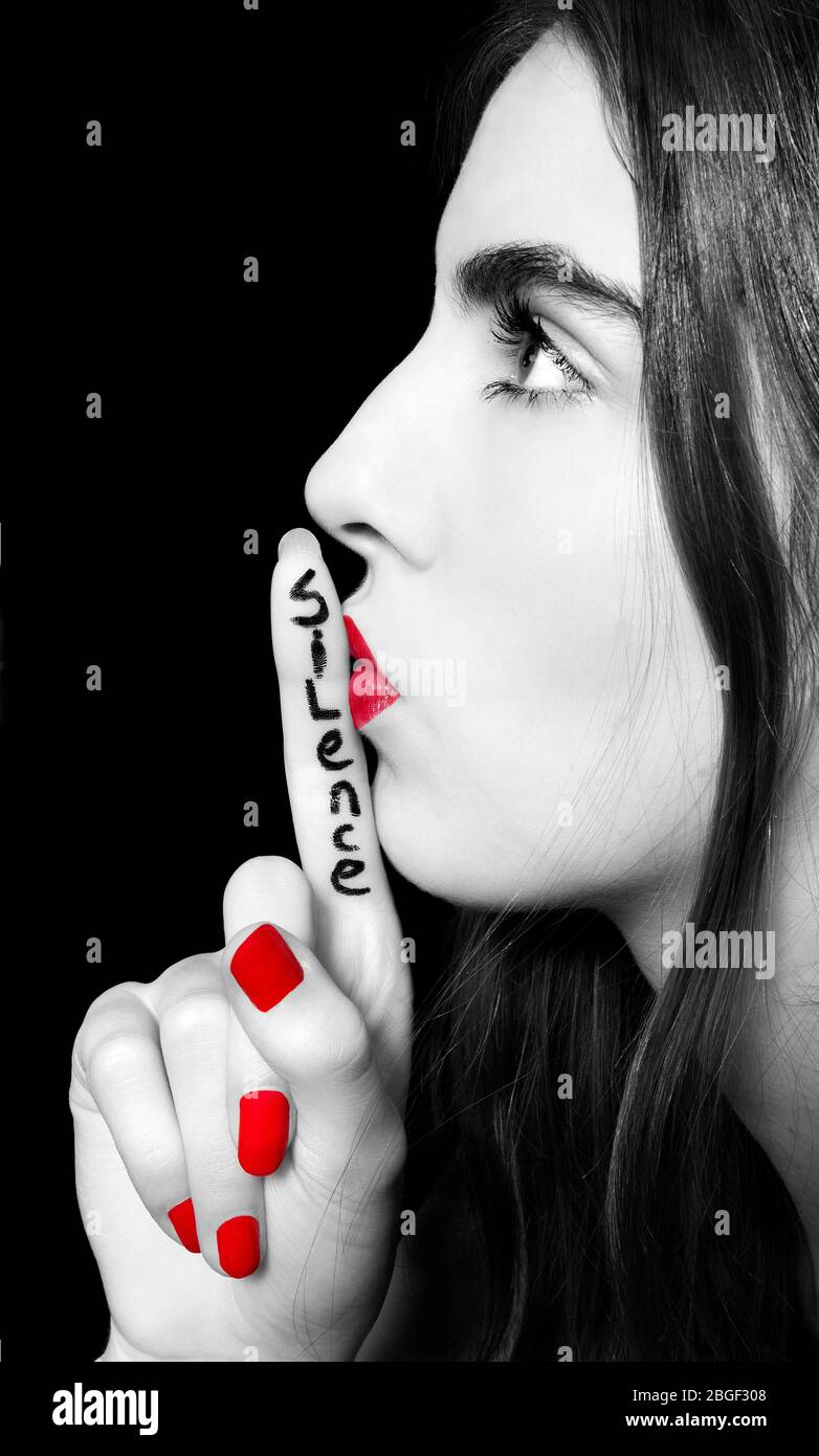 Woman asking for silence with finger on lips hush hand gesture. Isolated on a black background Stock Photo