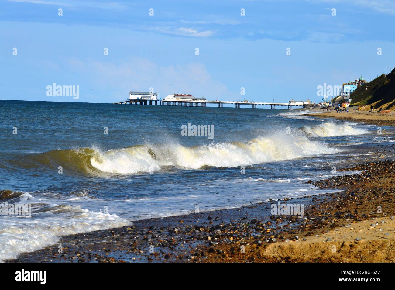 Cromer pier in the summer with blue skies and waves. Norfolk, England Stock Photo