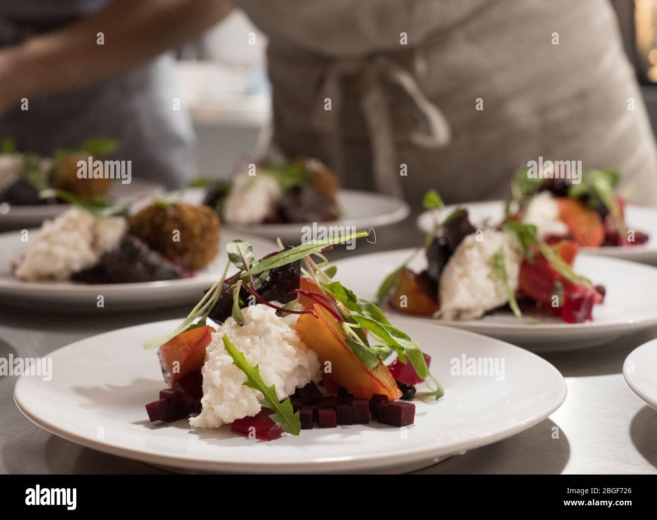 Roasted root vegetables with a horseradish and celeriac remoulade, being plated up at a supper club Stock Photo