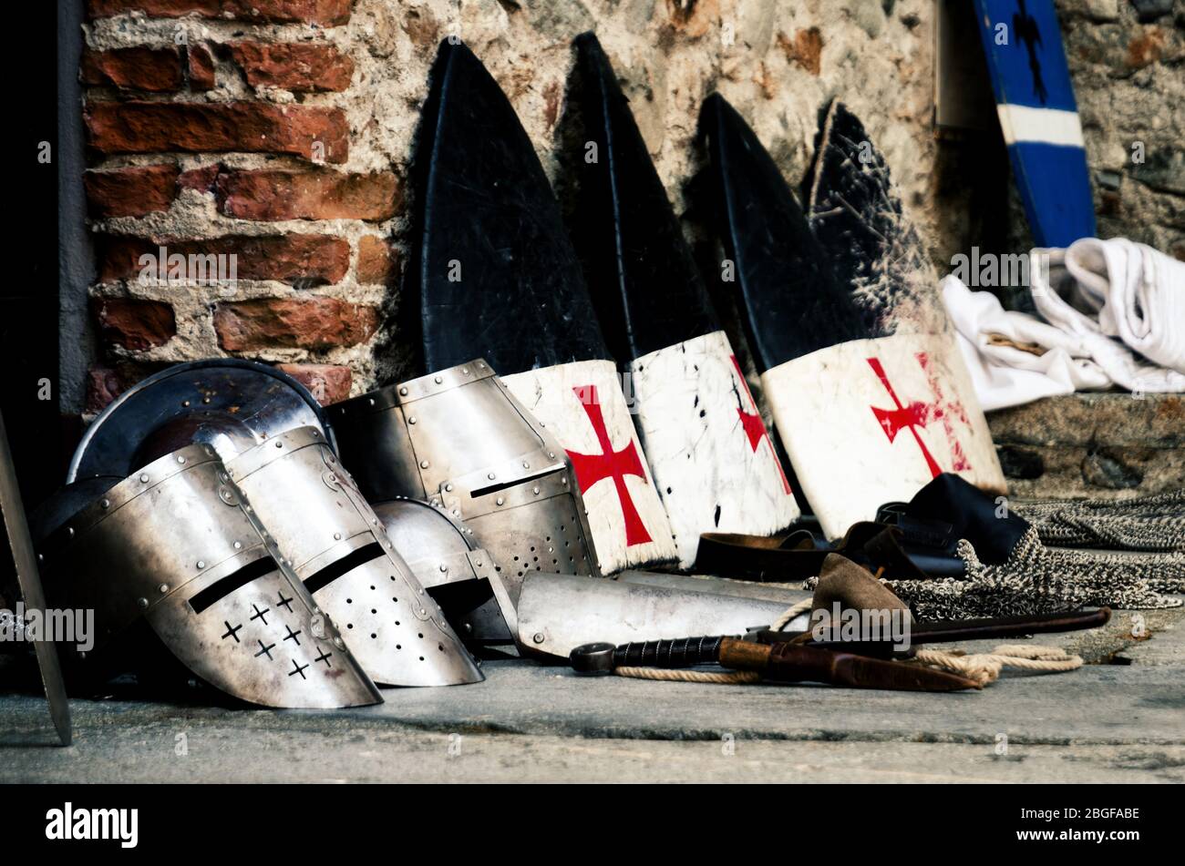 Medieval weapons, shields and helmets from the crusade age on a castle floor during an historical reenactment Stock Photo