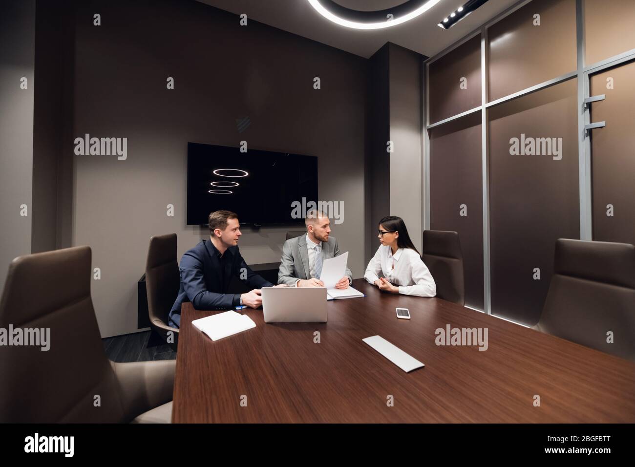 Portrait of three co-workers discussing business plan in office Stock Photo