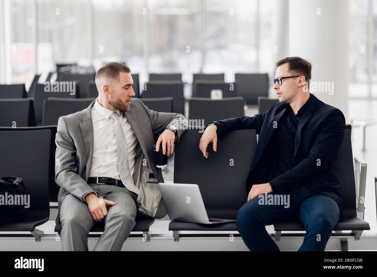 Business colleagues waiting at airport lounge standing and talking Stock Photo