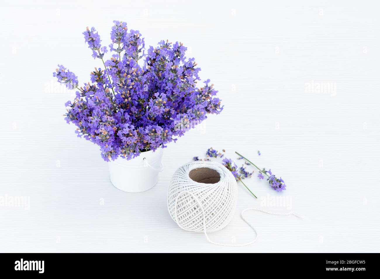 Fresh lavender in small white bucket and hemp ball on white wooden background. Stock Photo