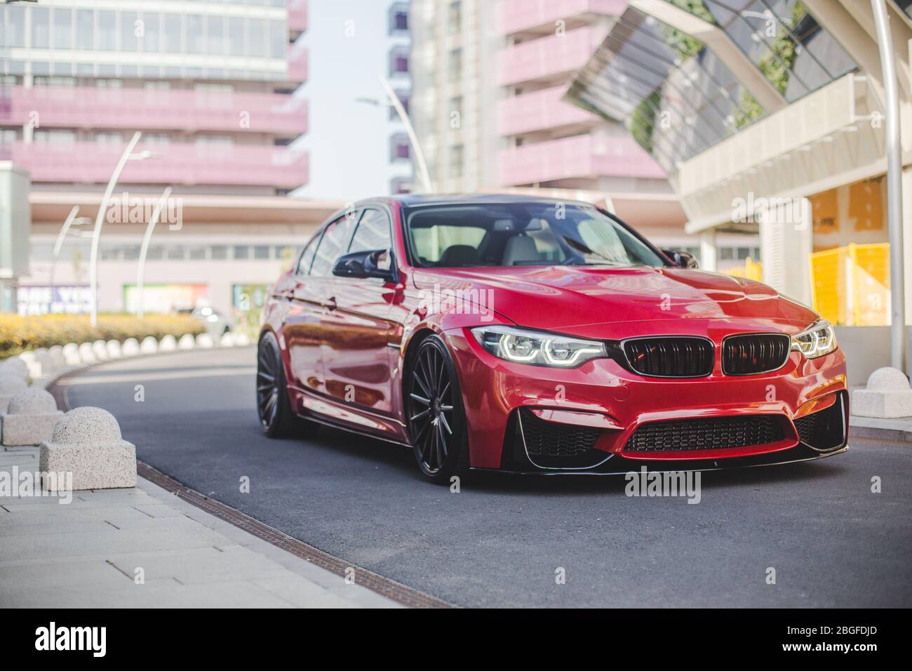 Red universal sedan touring in the city streets, across modern ...