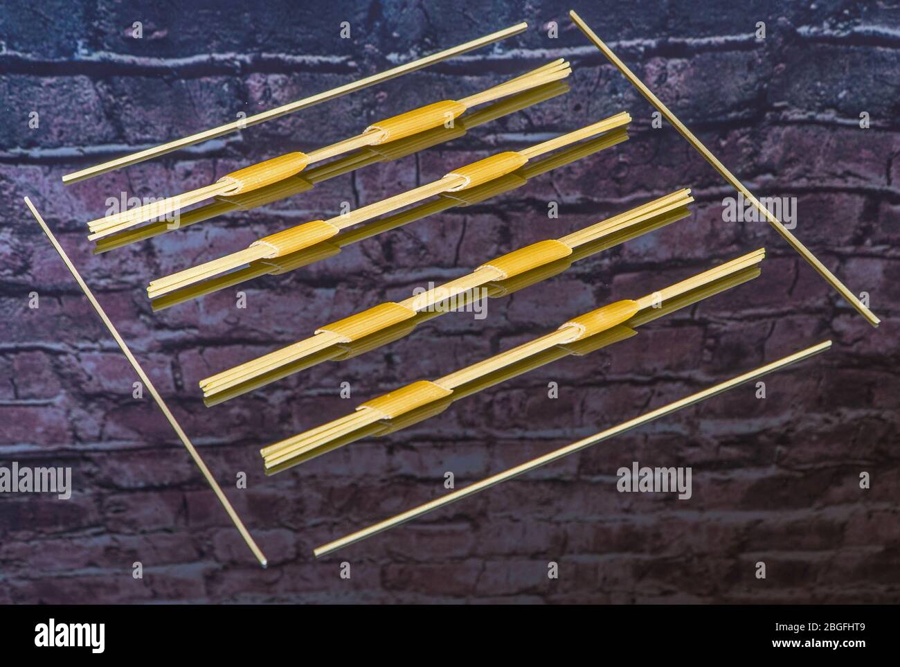 Spaghetti fed through penne pasta and framed on reflective surface Stock Photo