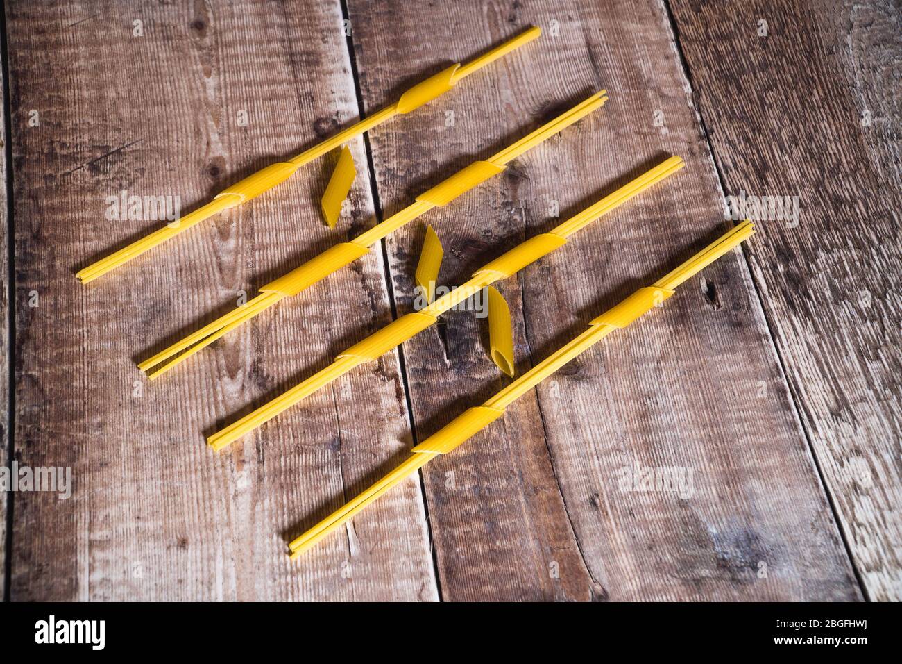 Spaghetti fed through penne pasta and framed on wooden surface Stock Photo