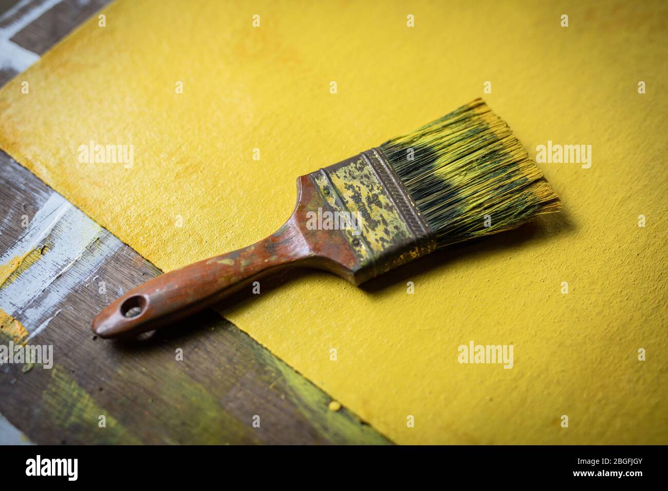 A paintbrush with yellow paint in and artists studio. Stock Photo
