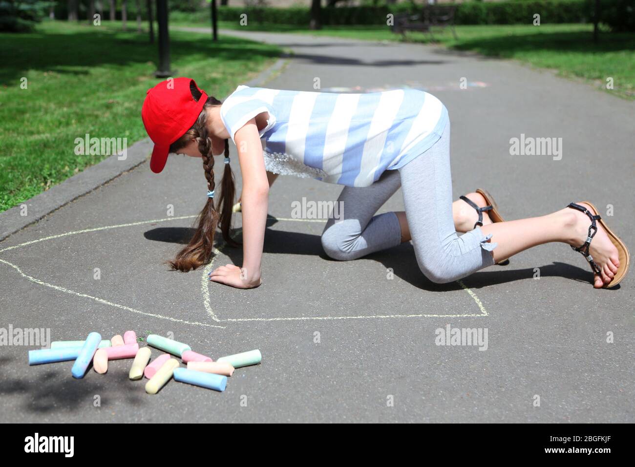 Cute girl drawing with chalk on asphalt Stock Photo - Alamy