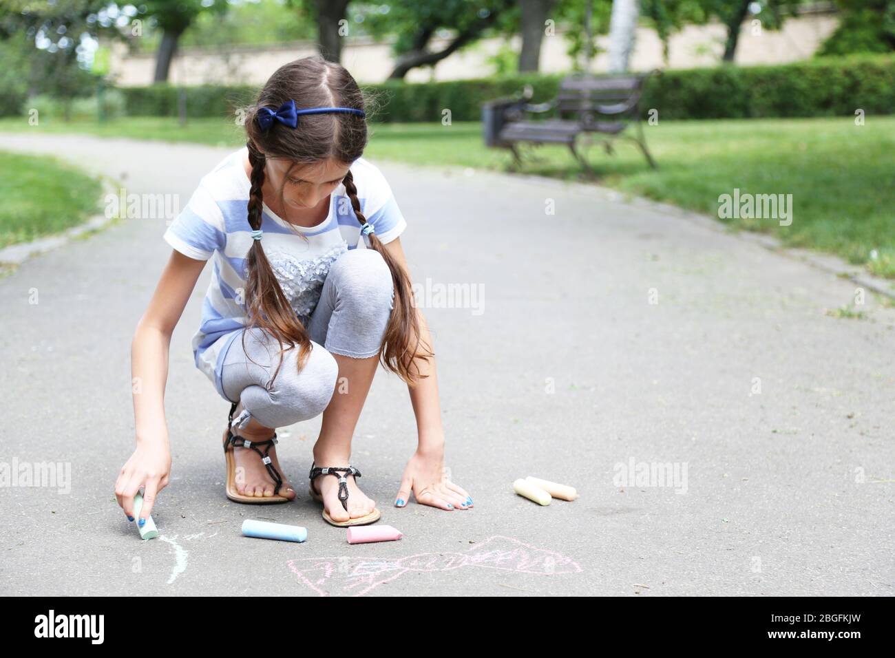 Cute girl drawing with chalk on asphalt Stock Photo - Alamy