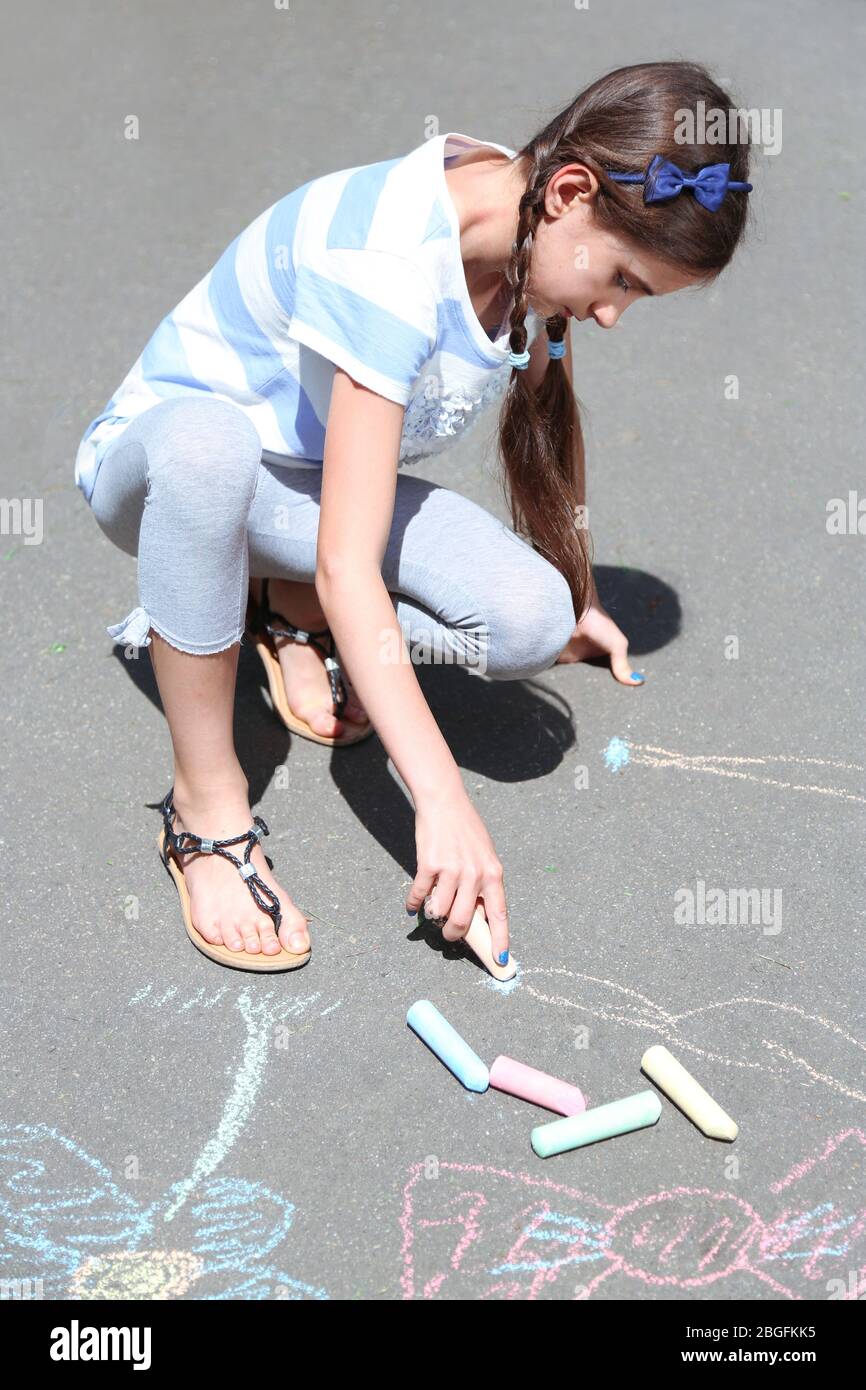 Cute girl drawing with chalk on asphalt Stock Photo - Alamy