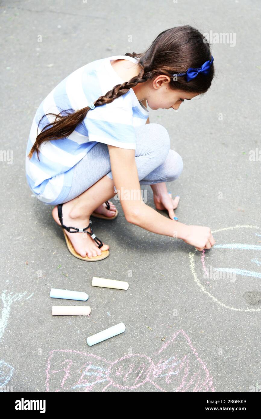 Cute girl drawing with chalk on asphalt Stock Photo - Alamy
