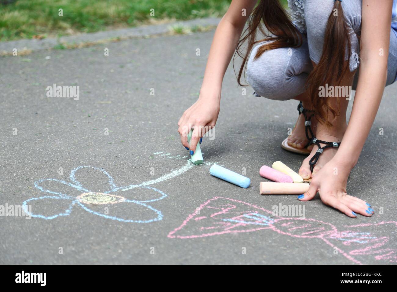 Cute girl drawing with chalk on asphalt Stock Photo - Alamy