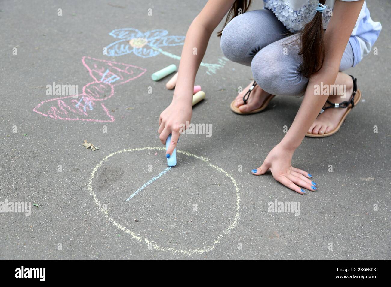 Cute girl drawing with chalk on asphalt Stock Photo - Alamy