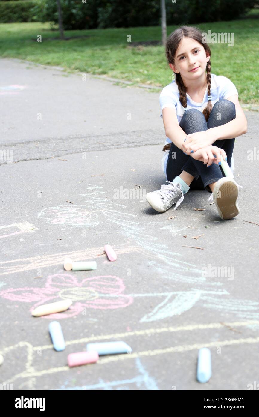 Cute girl drawing with chalk on asphalt Stock Photo - Alamy