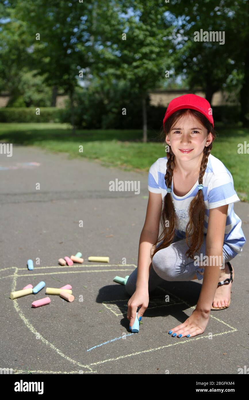 Cute girl drawing with chalk on asphalt Stock Photo - Alamy