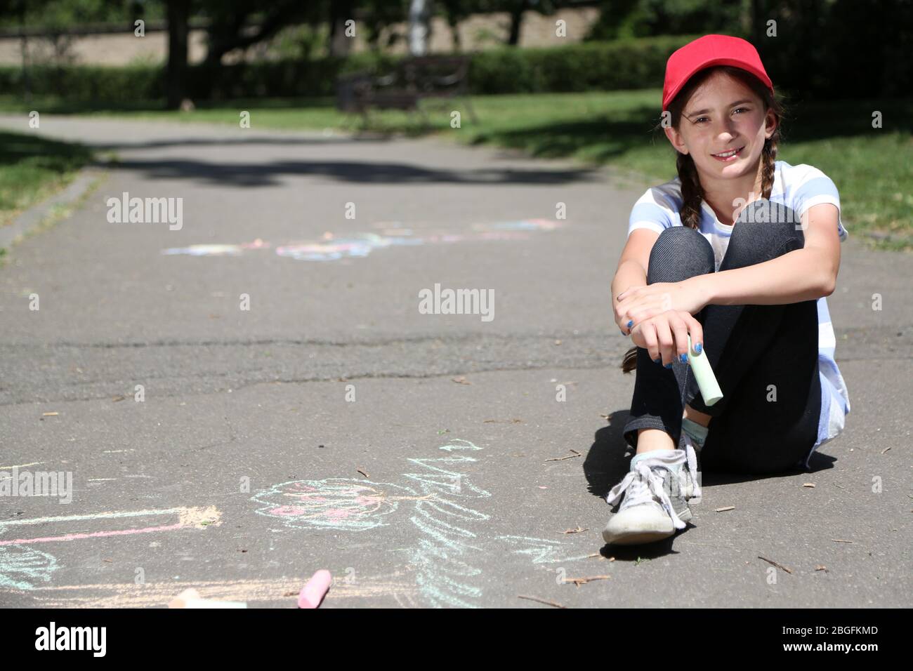 Cute girl drawing with chalk on asphalt Stock Photo - Alamy