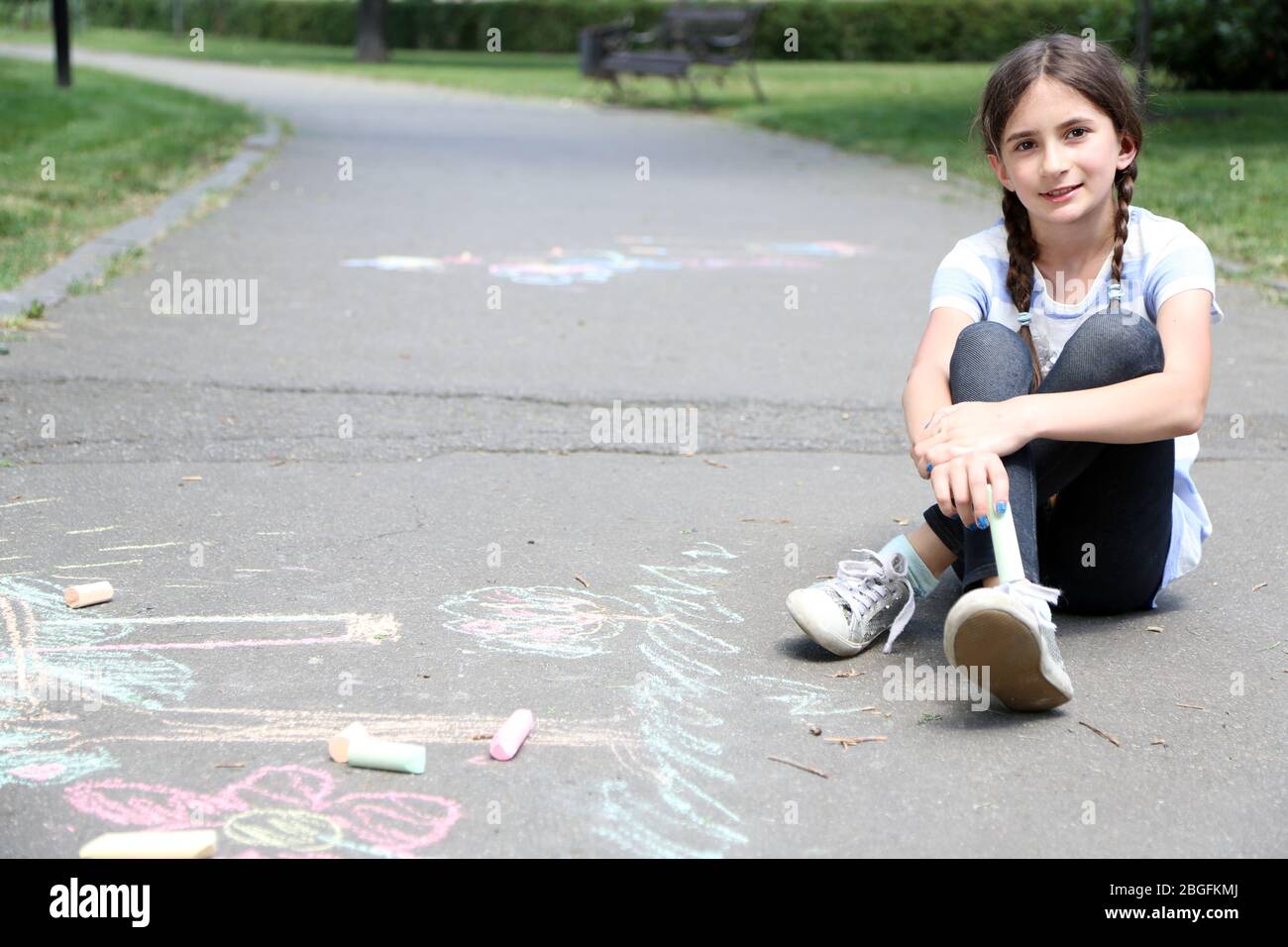 Cute girl drawing with chalk on asphalt Stock Photo - Alamy