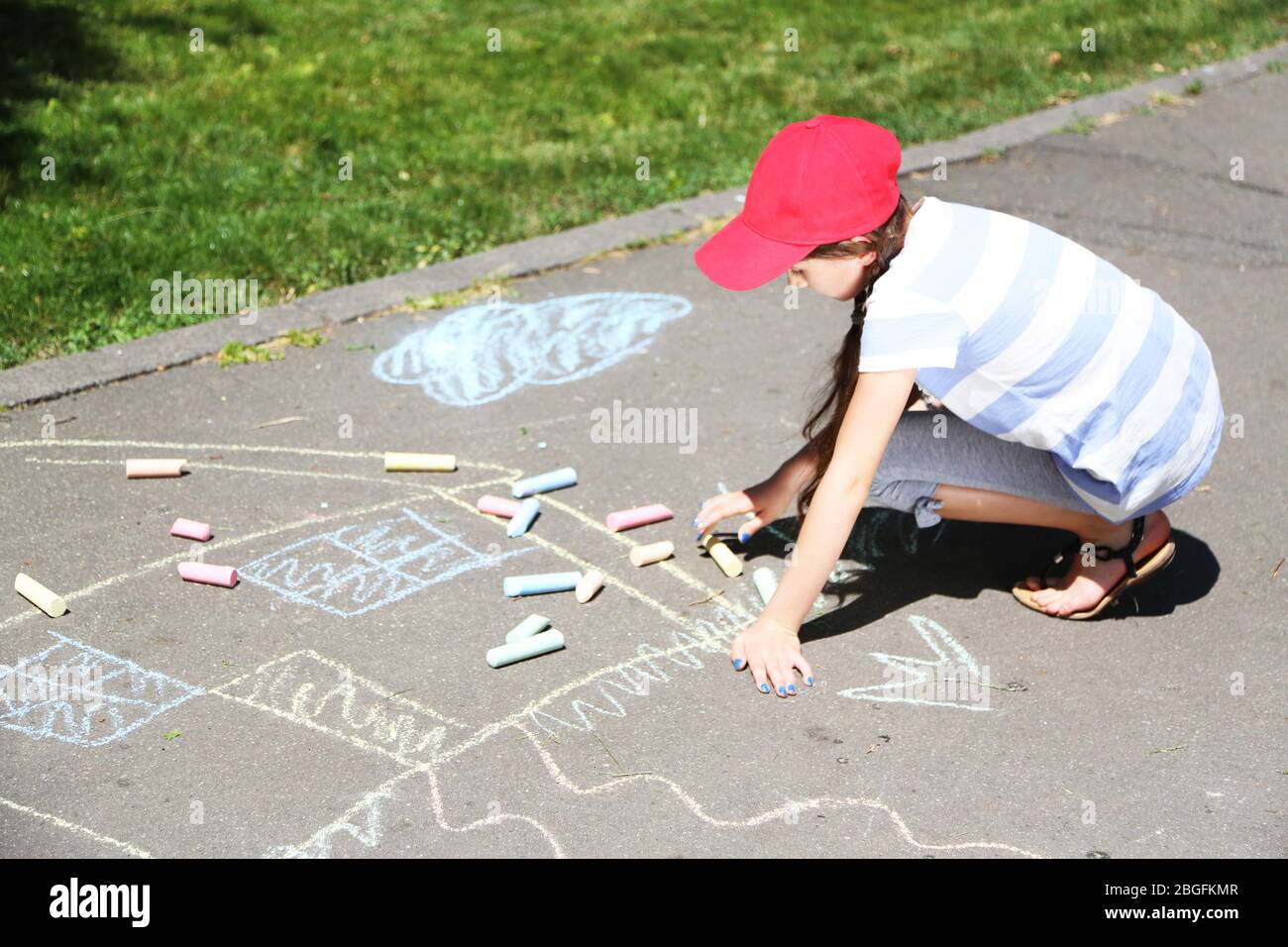 Cute girl drawing with chalk on asphalt Stock Photo - Alamy