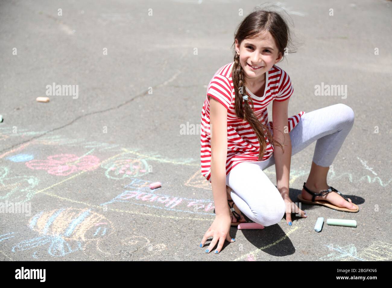 Cute girl drawing with chalk on asphalt Stock Photo - Alamy