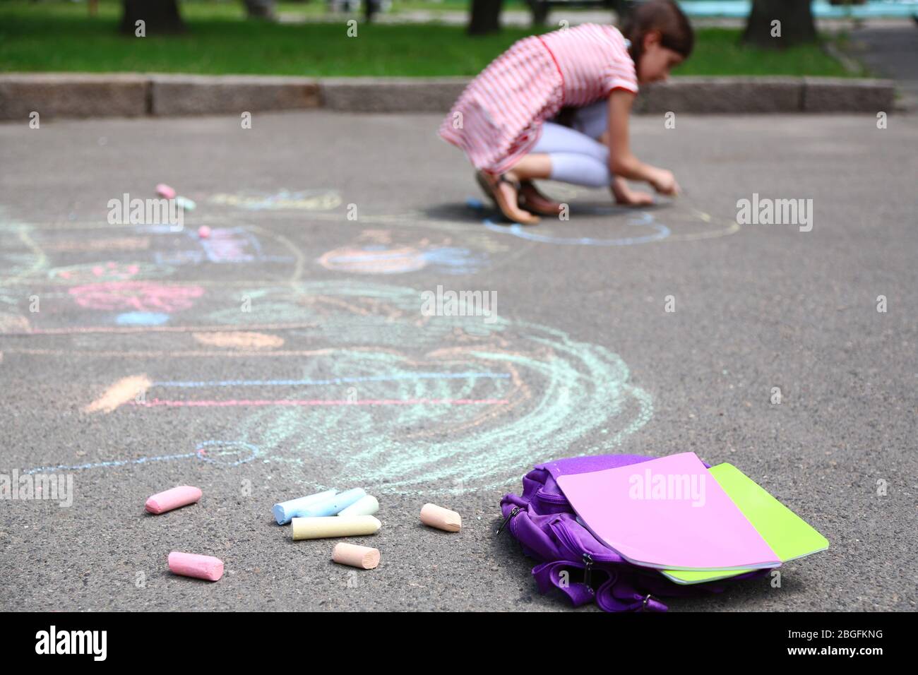 Cute girl drawing with chalk on asphalt Stock Photo - Alamy