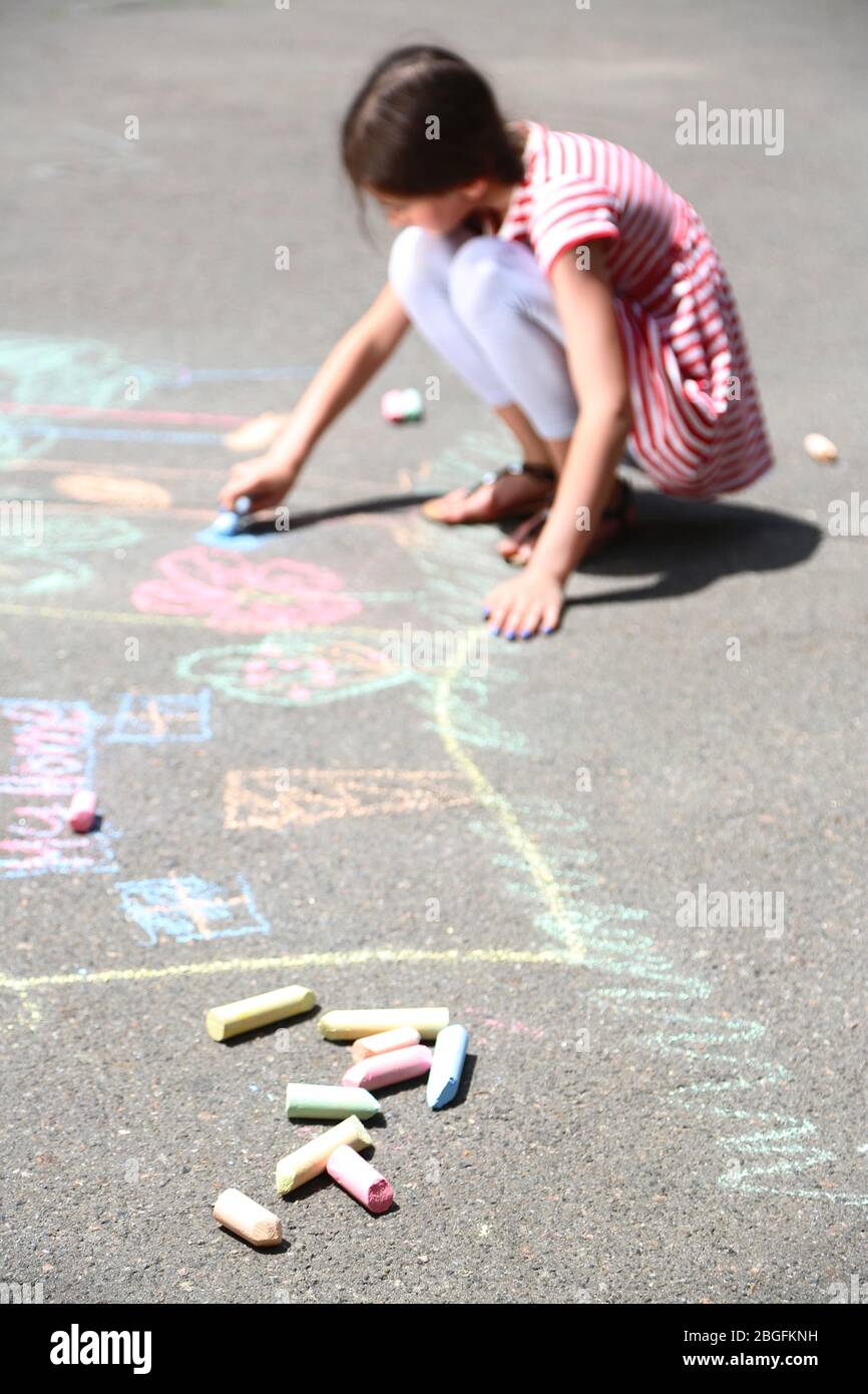 Cute girl drawing with chalk on asphalt Stock Photo - Alamy