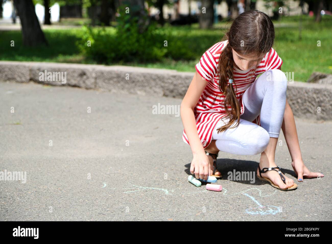 Cute girl drawing with chalk on asphalt Stock Photo - Alamy