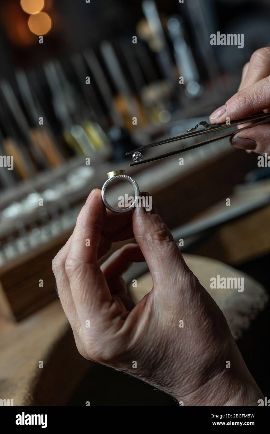 A goldsmith at work in the studio setting a diamond into a ring. Stock Photo